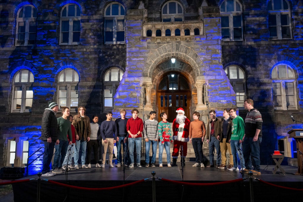 The Georgetown Chimes, a group of 15 tenor, baritone, and bass singers, sing in front of Healy Hall with Santa Claus.