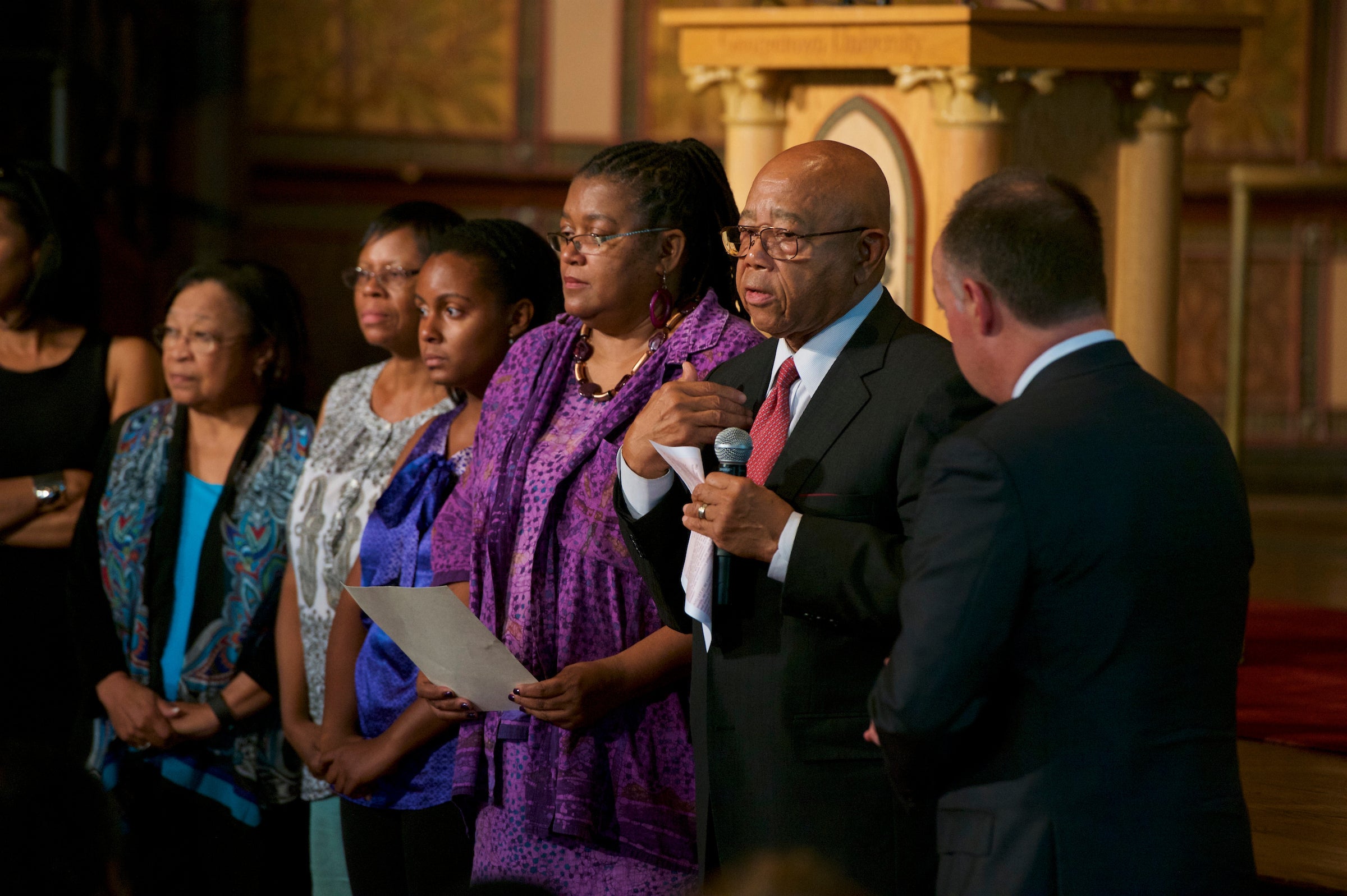A group of people stand on stage, including President DeGioia and Joseph Stewart.