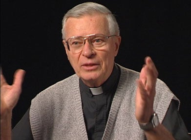 George Aschenbrenner, S.J., a white man with greying hair and glasses, wearing a minister's collar and beige sweater vest.