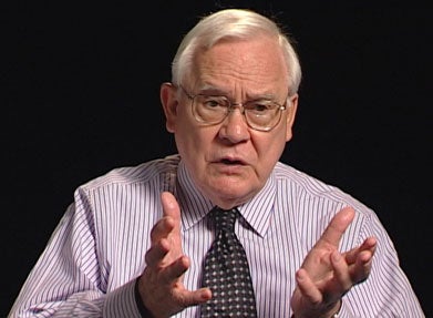 Howard Gray, S.J., a white man with grey hair and glasses, wearing a purple collared shirt and a dark tie.