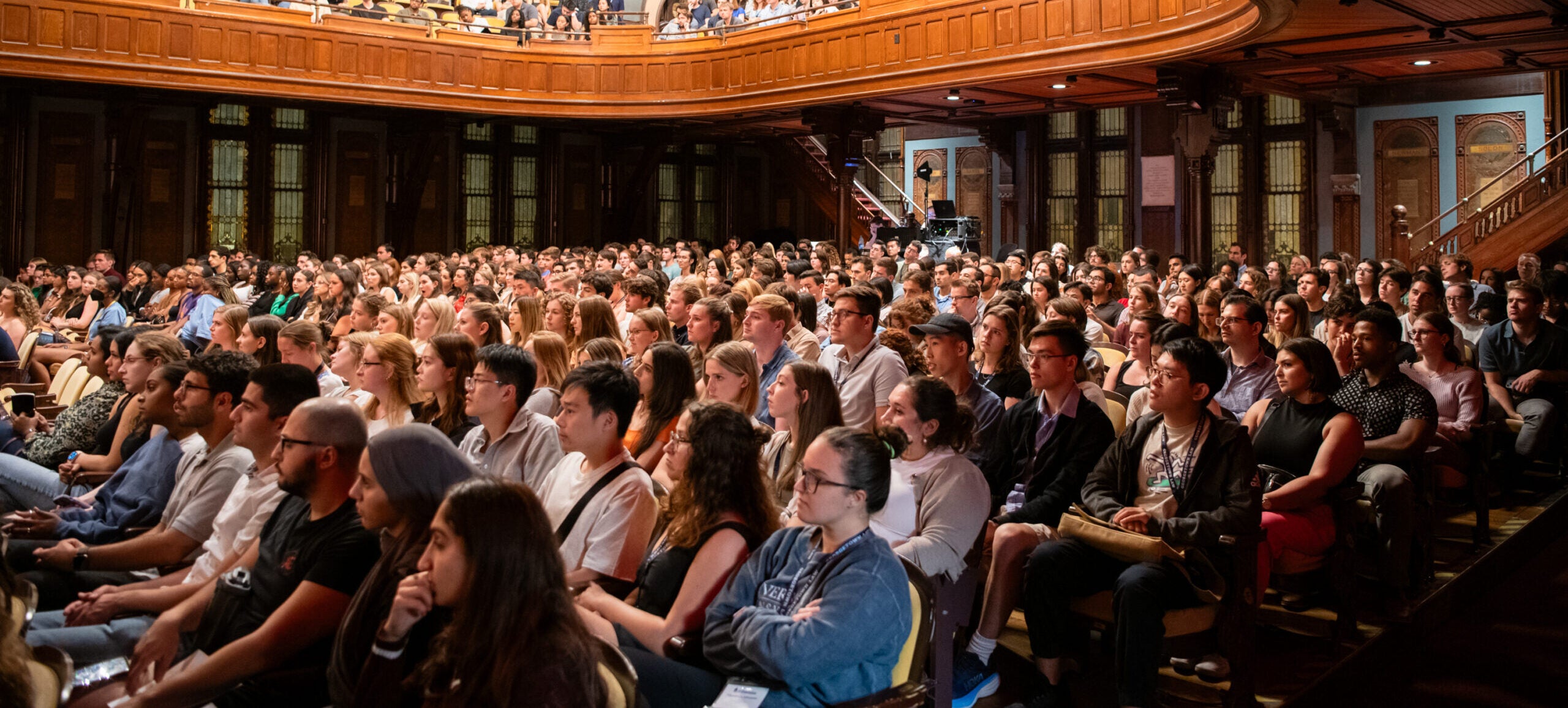 Students fill the audience in a two-tiered theater.