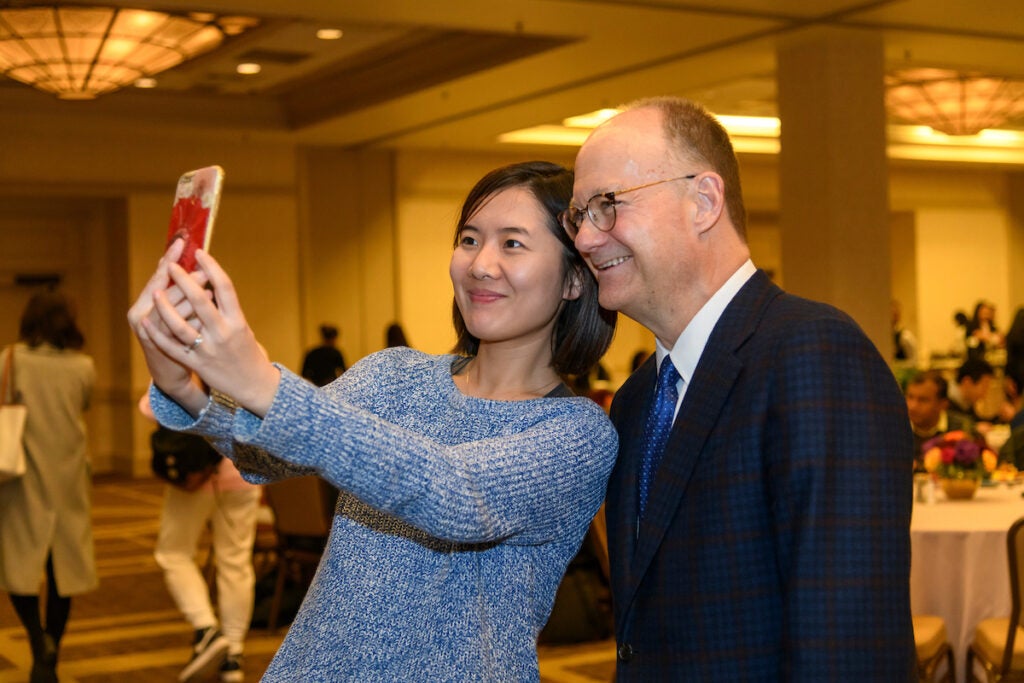 A student leans in to take a selfie with President DeGioia.