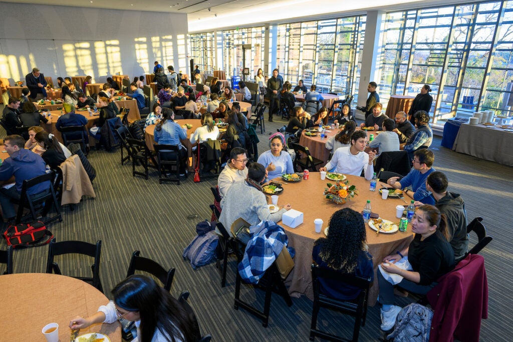 The Great Room of the Healy Family Student Center is filled with 8-top round tables. Each table is decorated with an orange tablecloth and fall foliage center piece. Nearly all of the tables are full, with students sitting, chatting, and enjoying a meal together.