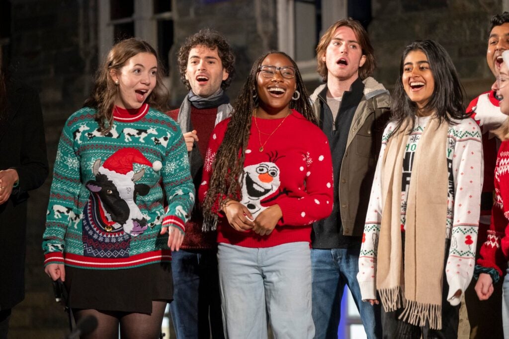 The Georgetown Saxatones, a mixed voice singing group, dressed in festive holiday sweaters, sings in front of Healy Hall.