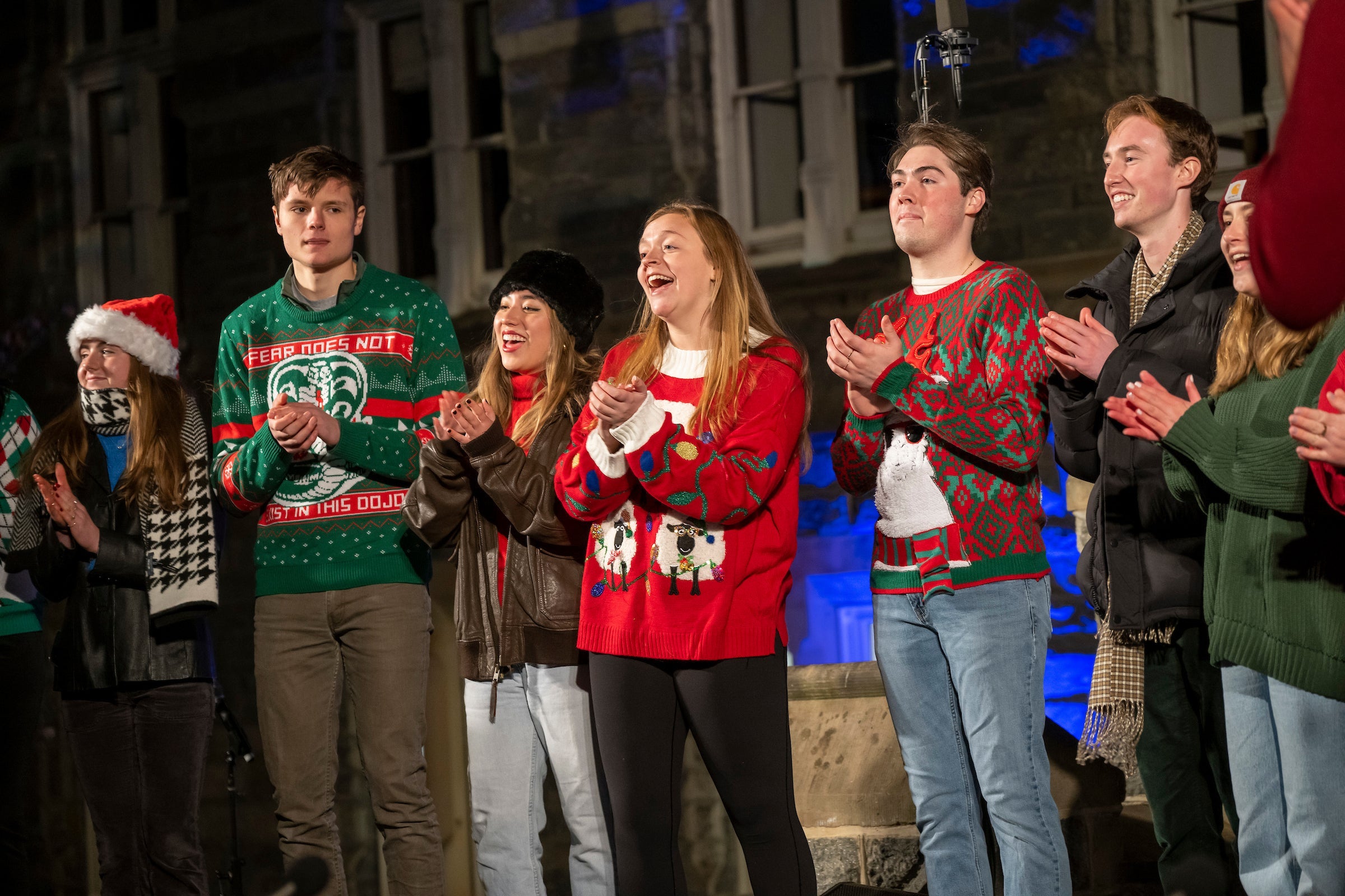 The Georgetown Phantoms, a mixed voice acapella group perform. Only 7 are pictured. They are wearing festive holiday sweaters.