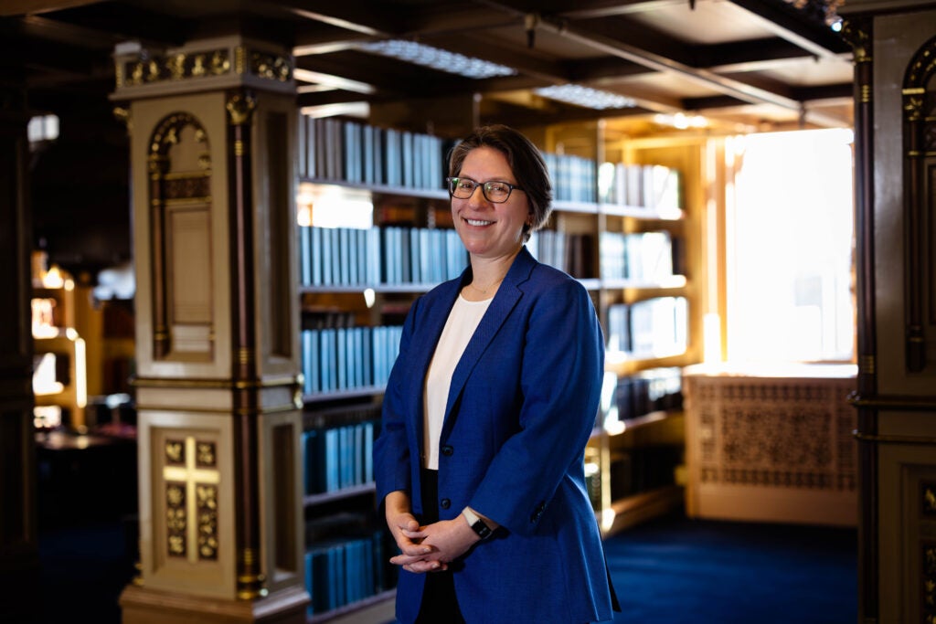 Headshot of Eloise Pasachoff. She is wearing a blue suit and standing amid the stacks of books in Riggs Library.