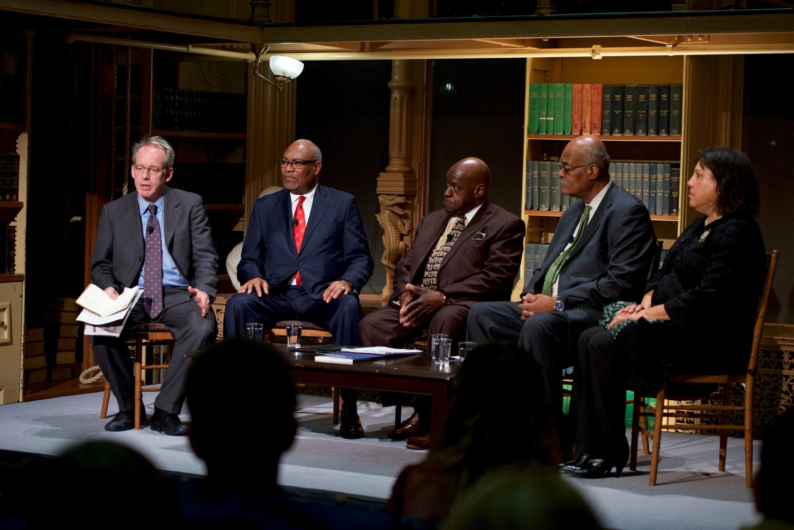 A white man, three black men, and a black woman are seated and leading a panel discussion.