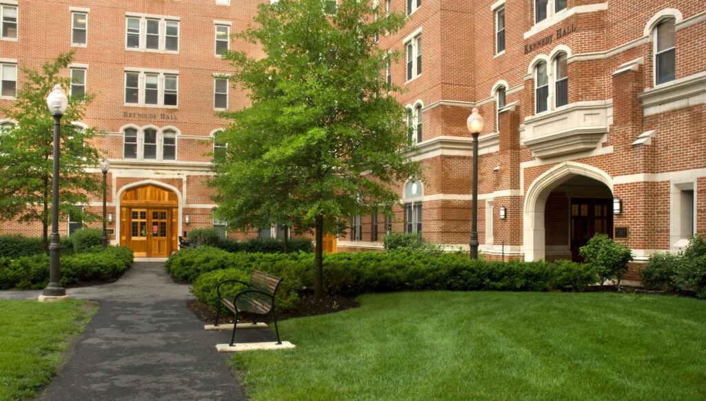 The brick exteriors of Reynolds and Kennedy Halls meet at a right angle, surrounding a grassy coartyard.