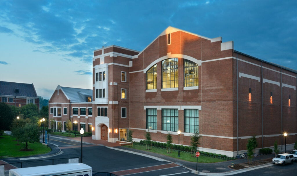 The exterior of the Thompson Athletics Center, a multi-level brick building filled with large windows, facing a paved vehicle turnaround.