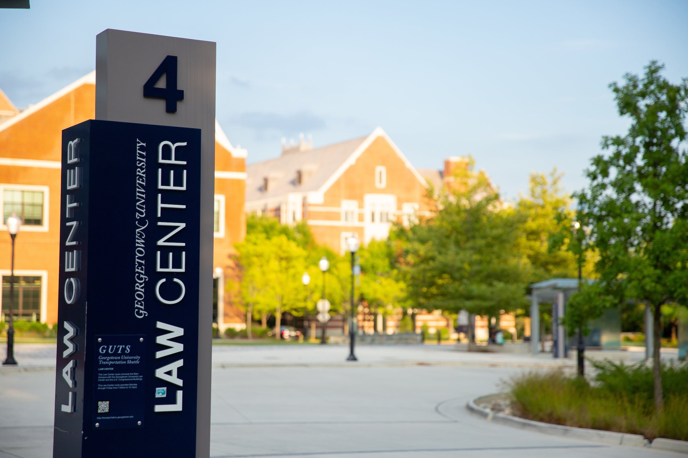 A shuttle bus stop sign for the Georgetown University Law Center, labeled number 4 in a paved bus turn-around, in front of the McDonough Arena.