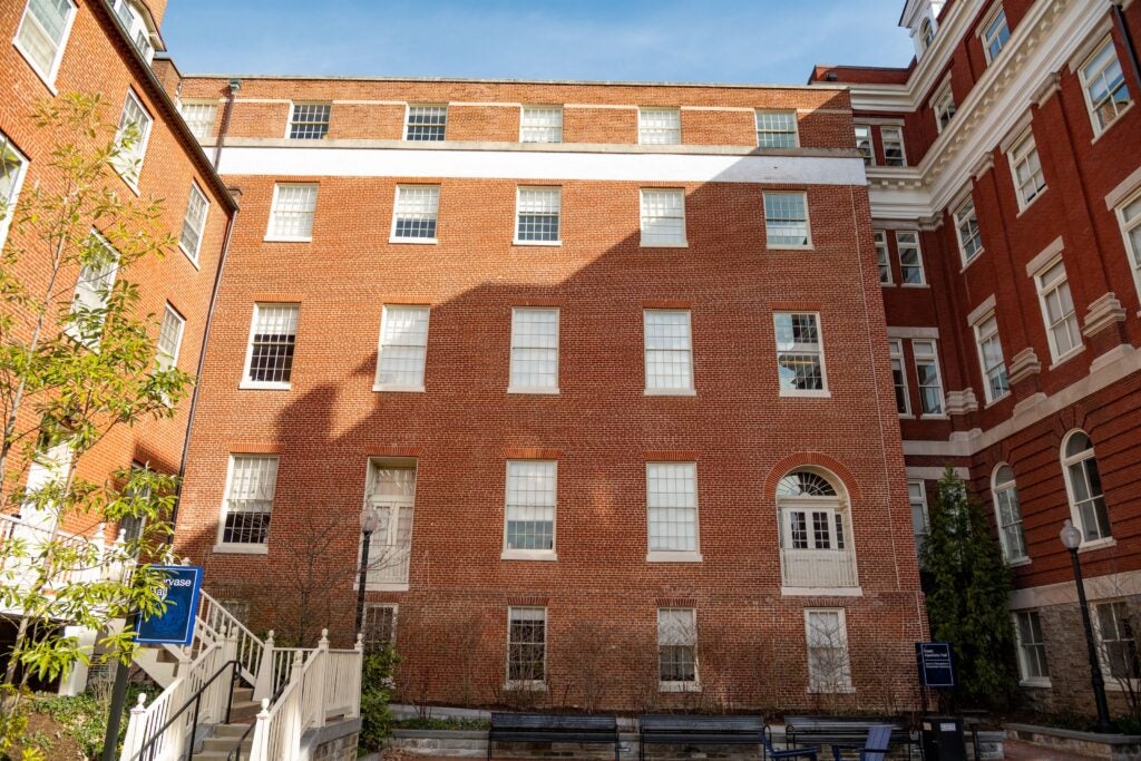 Three multi-story brick buildings stand at right-angles to each other, forming a u-shape.