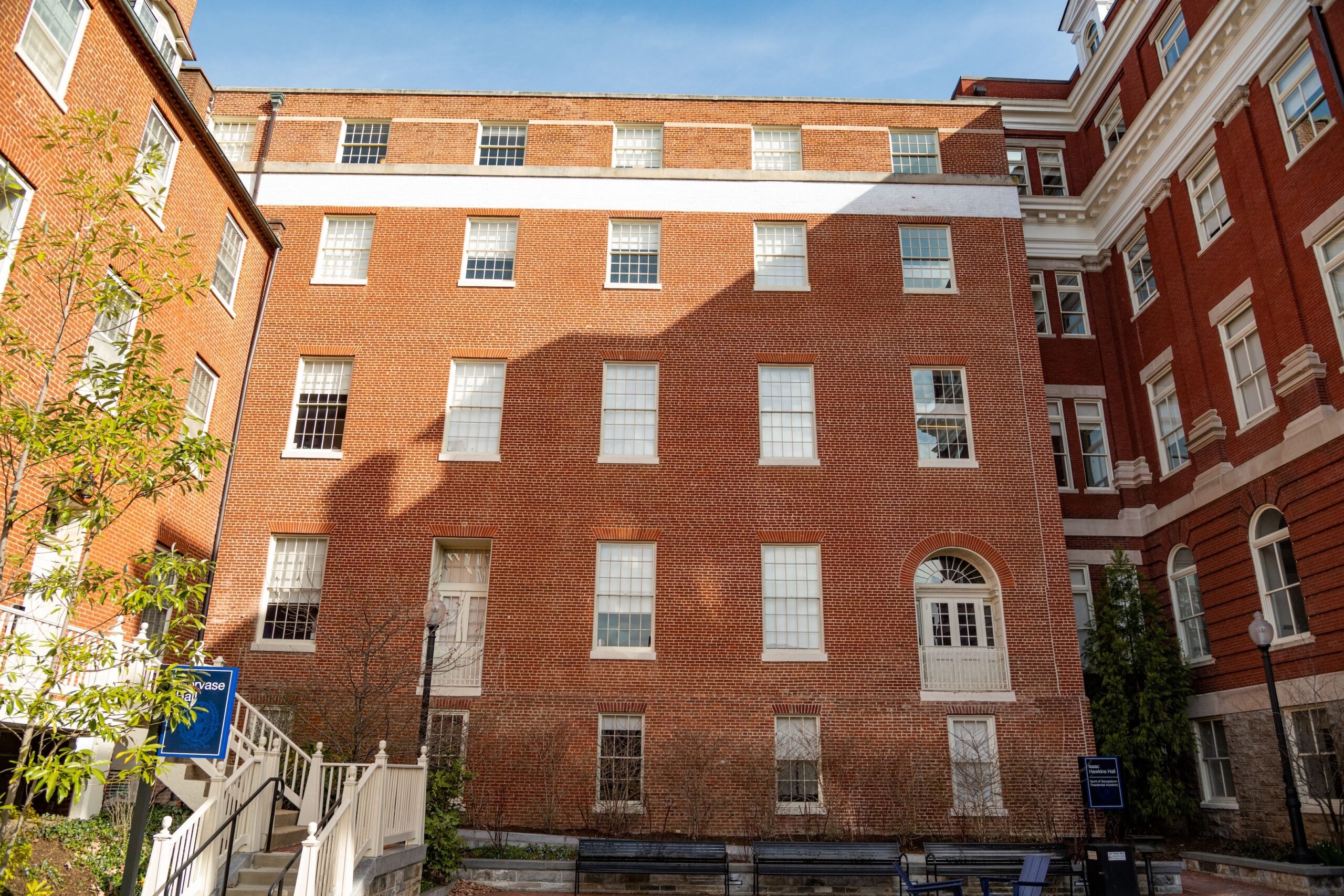 Three multi-story brick buildings stand at right-angles to each other, forming a u-shape.