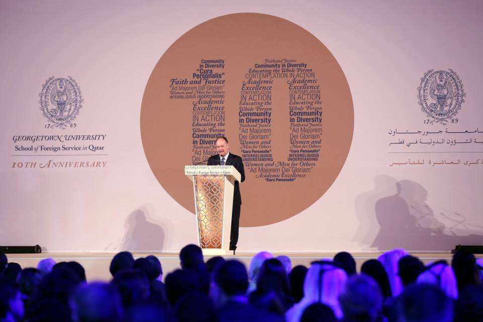 President DeGioia addresses a seated audience from a podium. Behind him is a large backdrop with the number 10 printed.