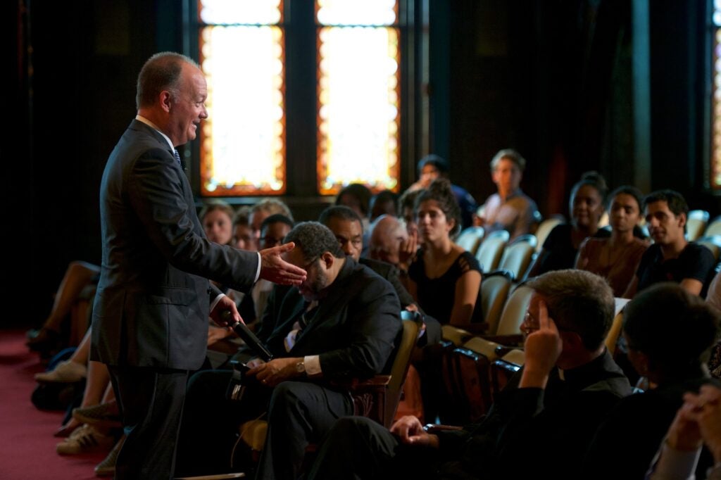 President DeGioia stands in the middle of a seated audience.
