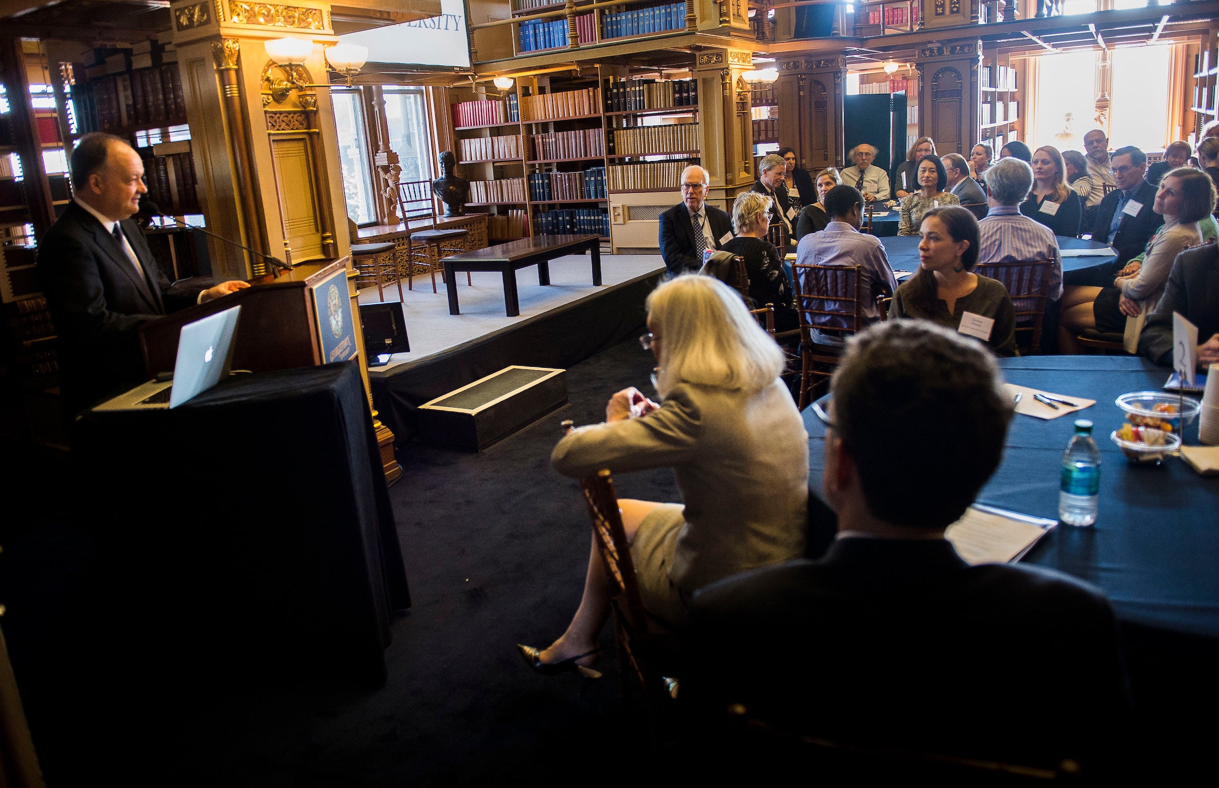 President DeGioia addresses an audience seated at round tables in Riggs Library.