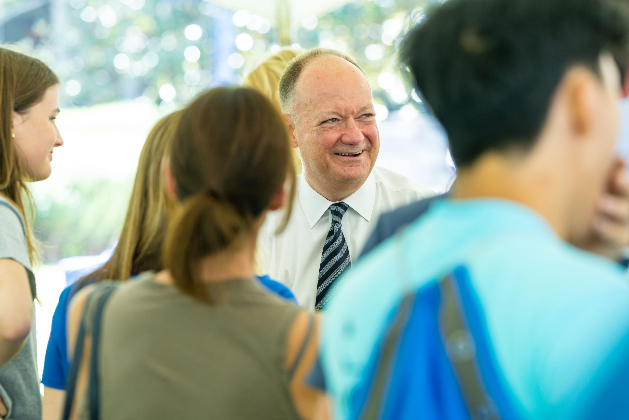 President DeGioia stands, smiling, among a group of students.