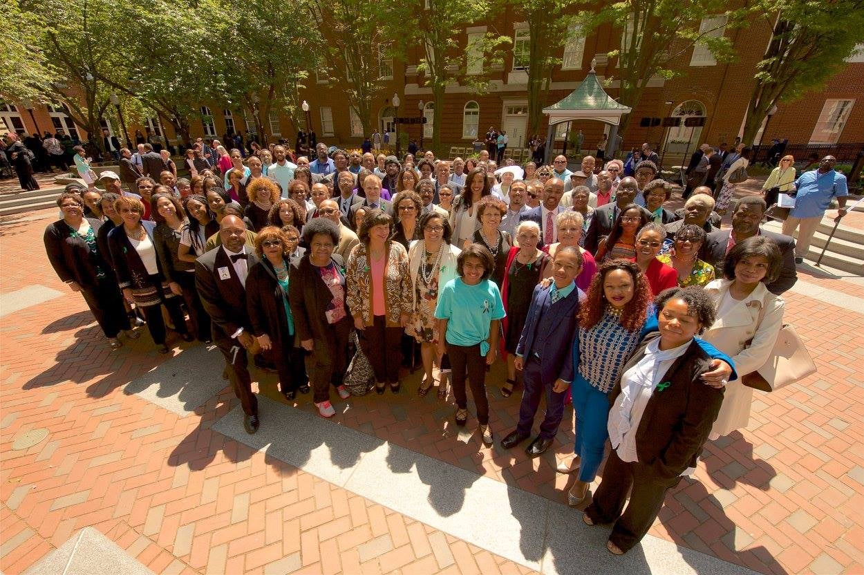 A large, mixed group of African-American people from the descendent community pose outside Hawkins Hall.