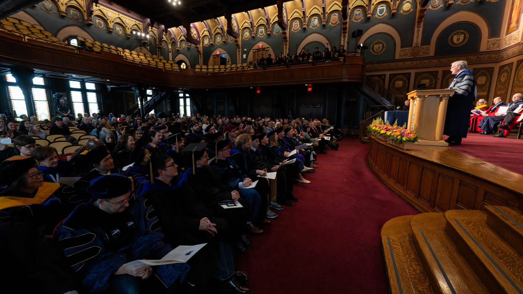 A view of an audience in a formal setting listening to a speaker.