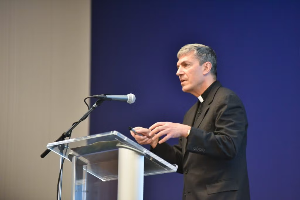 Close up view of Rev. Steve Katsouros, S.J. speaking from behind a podium.