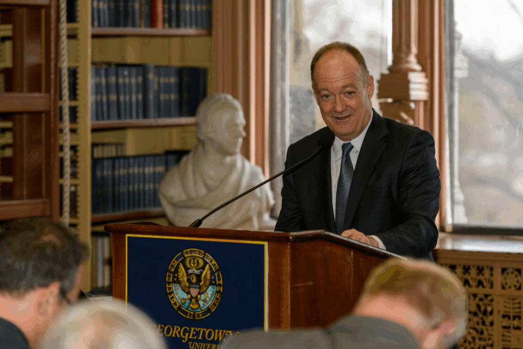 President John J. DeGioia speaks from behind a podium in Riggs Library.