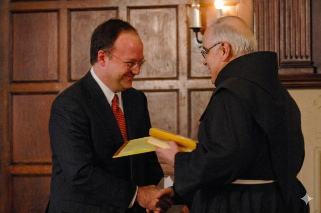 Then-President DeGioia and Rev. Fr. David-Maria Jaeger greet each other, shaking hands.