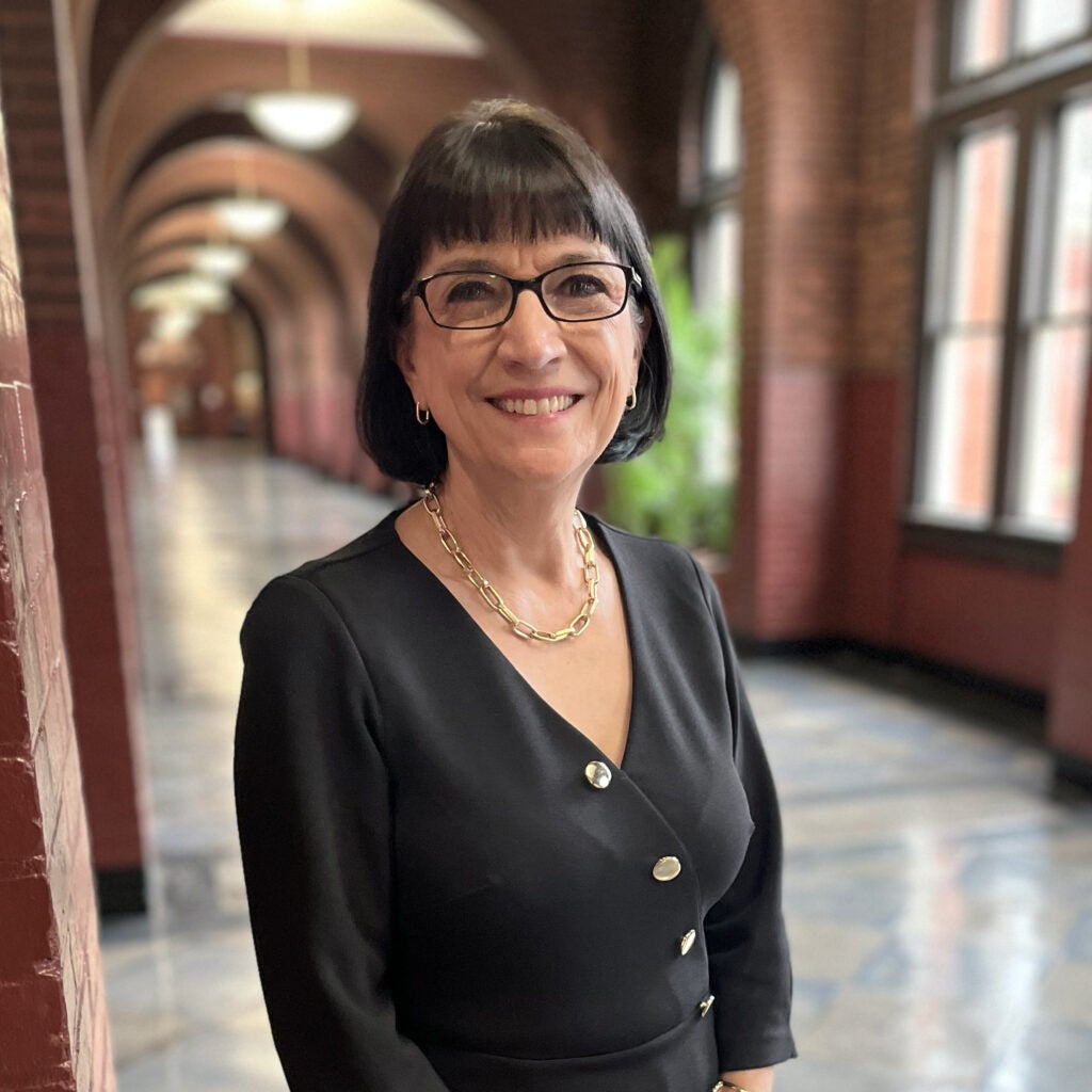 Marie Mattson, a woman with short black hair and glasses wearing a black suit.