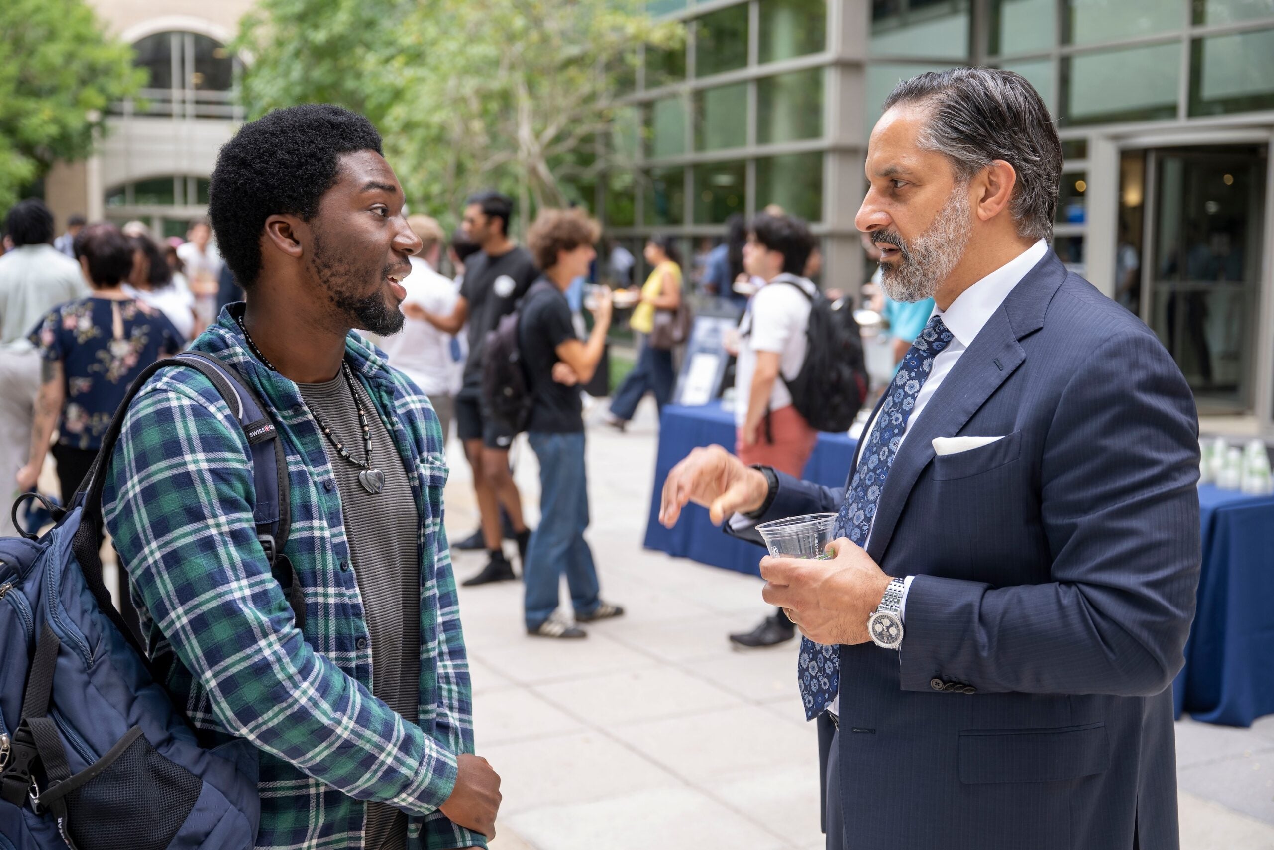 President Peñalver stands outside at the Capital Campus Welcome Back Barbecue, speaking with a student.