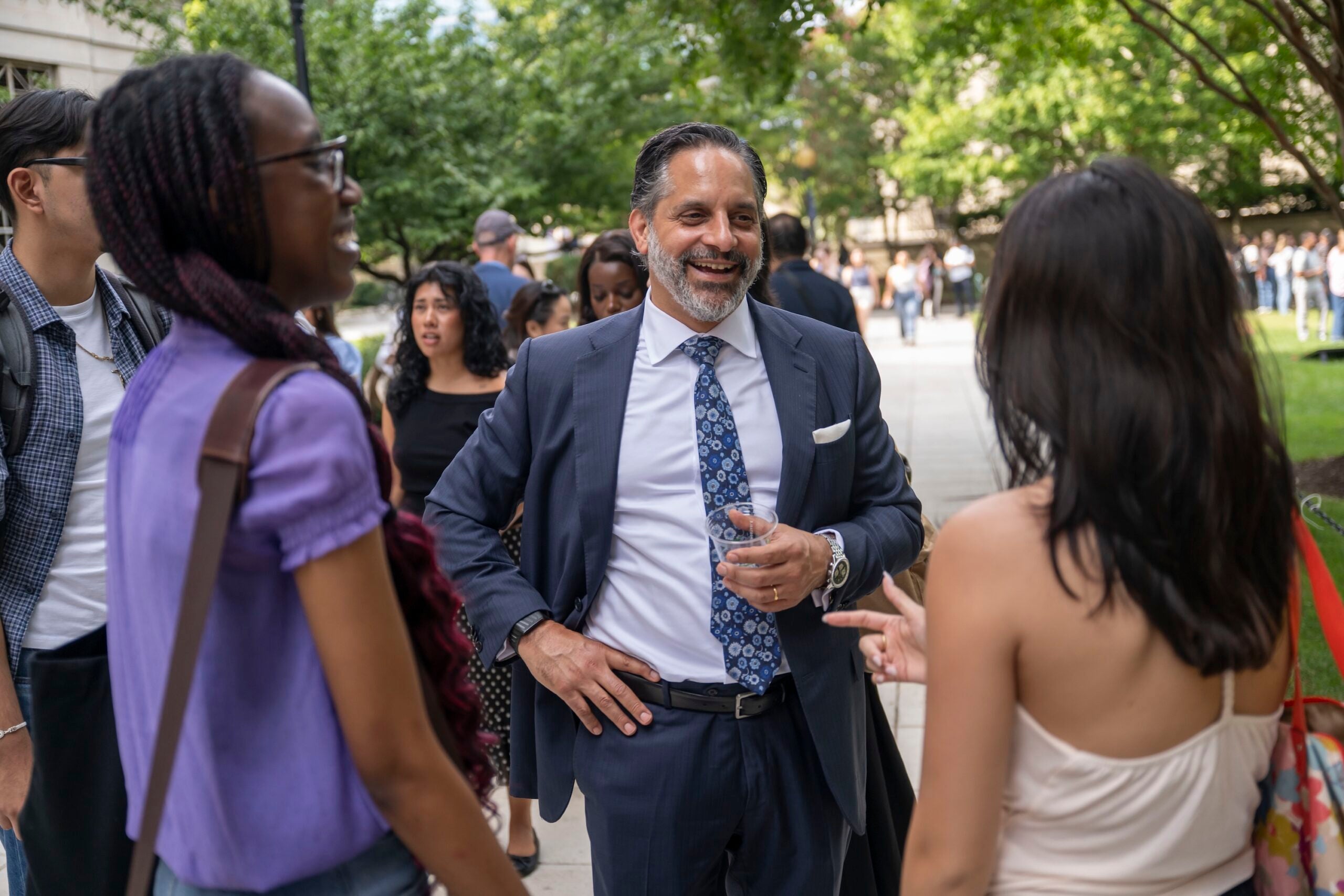 President Peñalver stands outside at the Capital Campus Barbecue, engaged in conversation with two students.